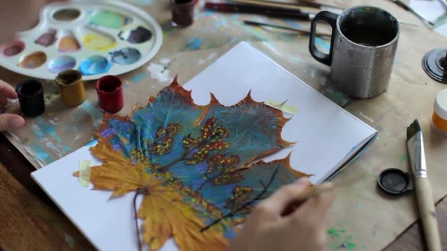 the girl paints a picture on a maple leaf