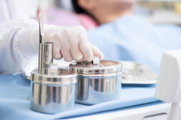 Metallic dentist tools close on and blue table sheet in a dentist clinic. with dentist hand 