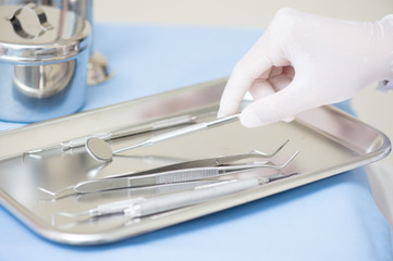 Metallic dentist tools close on and blue table sheet in a dentist clinic. with dentist hand 