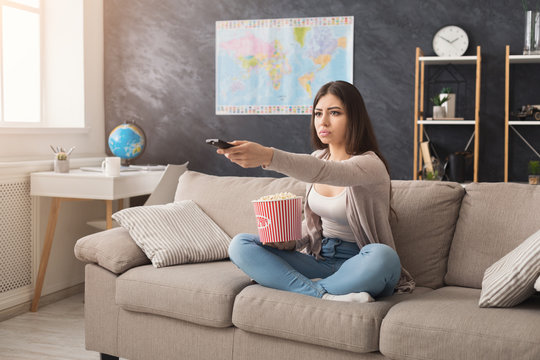 Young woman sitting on the couch and watching tv