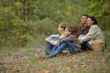 Naklejka na ściany i meble Happy smiling family in autumn forest sitting 