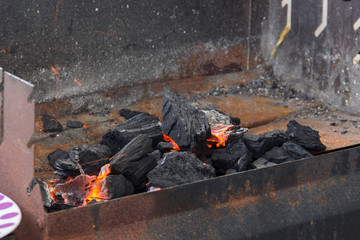 Black charcoal setting fire on rusty grill. Barbecue setting
