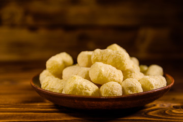 Ceramic plate with corn sticks on wooden table