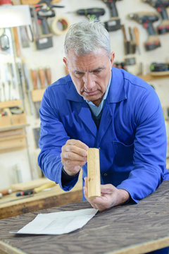 Senior man inspecting piece of wood in workshop