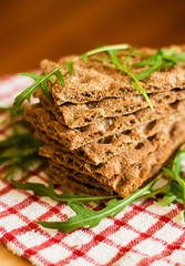 Crispbread with ruccola on tablecloth in red cage