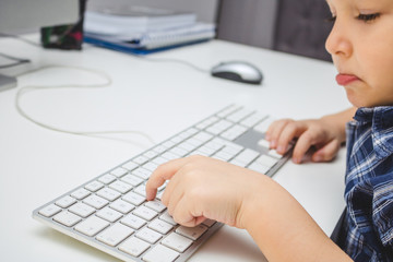 Close up of boy typing on computer keyboard.