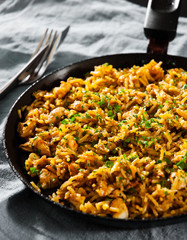 Chicken Breast with Rice and vegetables in a frying pan on dark wooden background