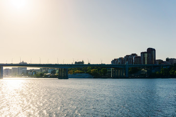 Fototapeta premium Silhouette of the city at sunset sun on a warm summer day from the opposite bank of the river
