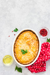 Cheddar ham potato gratin in baking dish on concrete background.Top view, space for text.