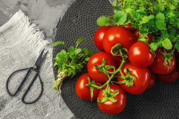 Bouquet of ripe red tomatoes with green baby salad on a wooden stand in a rustic style. Selective focus.