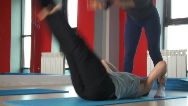 Female trainer help man with foot strengthening exercises in fitness class