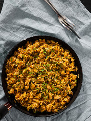 Chicken Breast with Rice and vegetables in a frying pan on dark wooden background