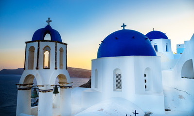 Scenic view of traditional cycladic white houses and blue domes in Oia village, Santorini island, Greece at sunset