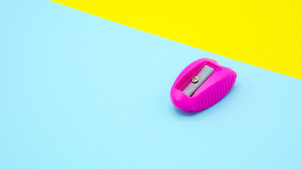 pink plastic pencil sharpener on blue and yellow background