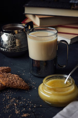 Glass cup of tea with biscuits, milk and honey