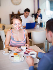 Obraz na płótnie Canvas Couple enjoying coffee with sweet dessert in cafe