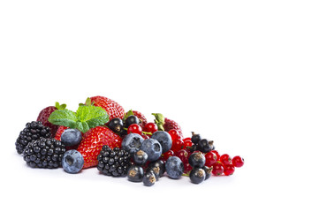 Ripe currants, blackberries, blueberries and strawberries with a mint leaf. Sweet and juicy fruits with copy space for text.  Background of mix fruits on a white background. Top view.