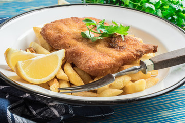 A piece of fried cod with fries on a plate.