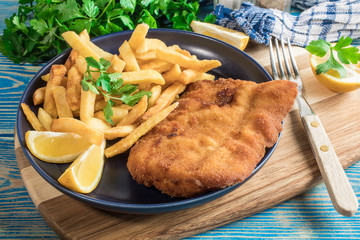 A piece of fried cod with fries on a plate.