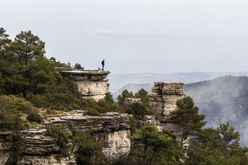 Hombre joven moreno mirando hacia abajo en el borde de la montaña