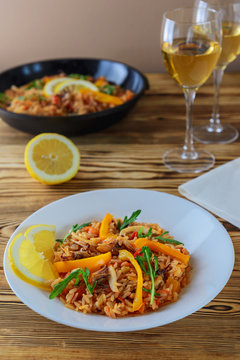 Paella with seafood with glasses of white wine on a wooden table