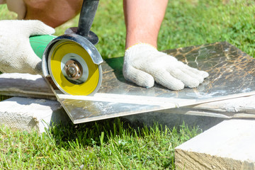 The plasterer master cuts the marble tile round the ceramic disc