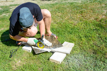 The plasterer master cuts the marble tile round the ceramic disc