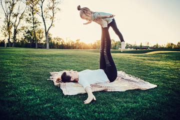 Mother practicing yoga with her daughter in the open air.