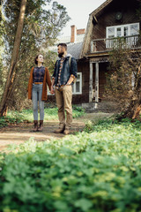 a pair of hipsters in a forest near an old house
