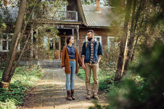 a pair of hipsters in a forest near an old house