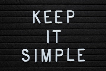 The words Keep It Simple in white plastic letters on a black letter board as a reminder for when planning your strategy