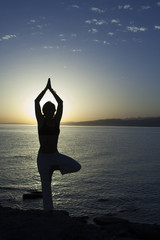 Beauty girl on beach in yoga pose, relax silhouette