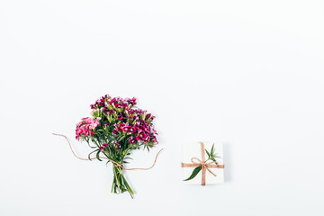 Top view of small bouquet and tiny gift box tied with twine