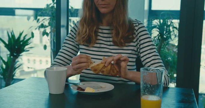 Woman eating croissant in slow motion