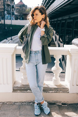 Young woman with wavy hair standing next to a bridge