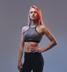 Fototapeta premium Sexy slim blonde girl in a sportswear posing in a studio.