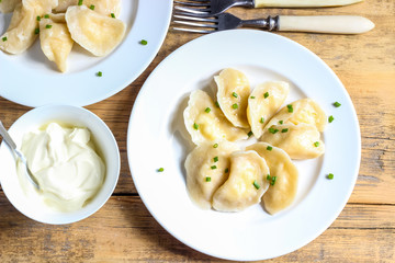 Russian, Ukrainian or Polish dish: varenyky, vareniki, pierogi, pyrohy. Dumplings, filled with cottage cheese and served with sour cream. Top view