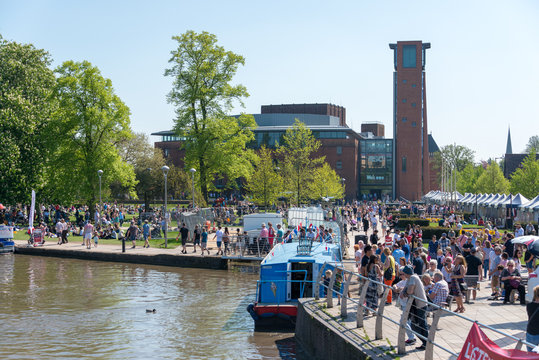 large crowd of people gather in front of the RSC by the canal basin and river 