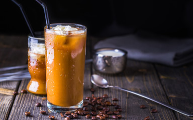 Ice coffee in a tall glass on dark natural desk.