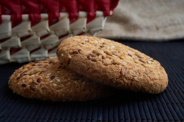 homemade oat cookies with sunflower seeds in and rear red checkered basket on wooden table