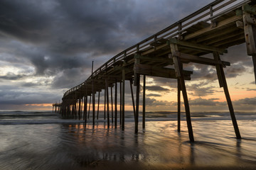 Obraz premium Fishing Pier with Colorful Sunrise and Dramatic Sky