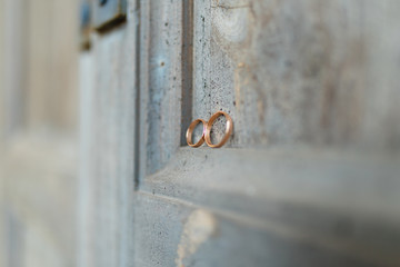 Wedding rings on a wooden door in the corner. Wedding rings hanging on rope over wooden background. Vintage image.