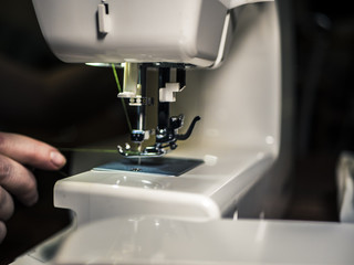 close up hand with thread using needle on a sewing machine