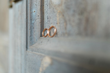 Wedding rings on a wooden door in the corner. Wedding rings hanging on rope over wooden background. Vintage image.