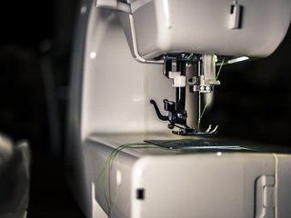 close up detaile view of a needle in a sewing machine on a textile faclory with black background