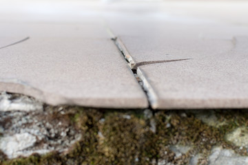 Close up of cracked ceramic tile on balcony floor surface due to improper construction material and...