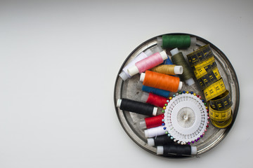horizontally background with multi-colored threads for sewing and needles, pins