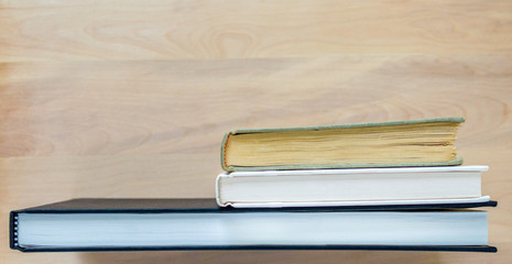 3 well worn books standing on end at a wooden desk with copy space