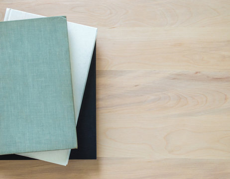 3 well worn books on a wooden desk with copy space