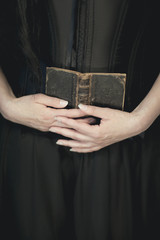 woman hands holding vintage old book, very dark atmospheric sensual rural, gothic studio shot can...